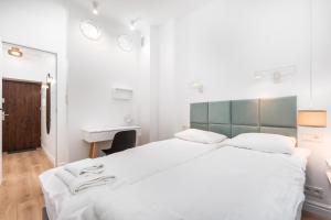 a white bedroom with a large bed and a desk at Apartament Plac Konstytucji by Your Freedom in Warsaw