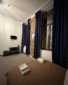 リヴィウにあるHotel Roverのベッドルーム1室(青いカーテン、デスク付)