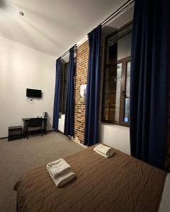a bedroom with a bed with blue curtains and a desk at Hotel Rover in Lviv