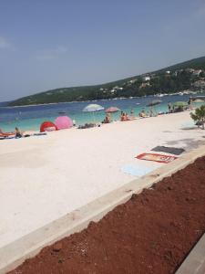 a beach with umbrellas and people in the water at Apartman Bonaca in Jadranovo +4 photos