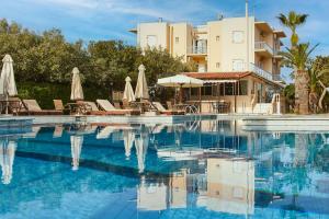 a swimming pool with chairs and umbrellas in front of a building at Klonos Anna in Egina