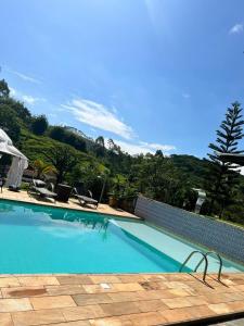 uma piscina com cadeiras e uma montanha ao fundo em Solar Azul Pousada Boutique em Miguel Pereira