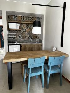 cocina con mesa de madera y sillas azules en Quarto em Quinta Santa Bárbara Ecoresort, en Pirenópolis