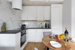 a kitchen with white cabinets and a wooden table at Apartament Superior & SPA Marina Dziwnów in Dziwnów