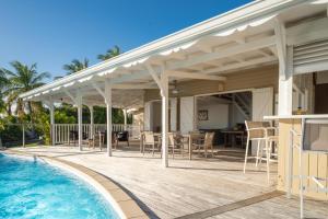 een witte pergola boven een terras naast een zwembad bij Villa Alexandra in Saint-François +20 foto's