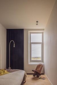 1 dormitorio con cama, ventana y silla en DUNE DU PALACE, en Zeebrugge