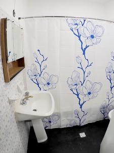 uma casa de banho com um lavatório branco e flores azuis na cortina do chuveiro em Departamento Bouquet em Barraquero