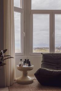 Zimmer mit 2 Fenstern, einem Tisch und einem Stuhl in der Unterkunft DUNE DU PALACE in Zeebrugge