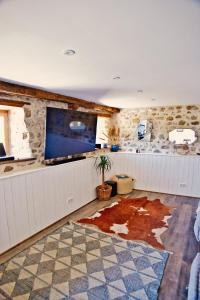 a living room with a large tv and a tile floor at Les Picardies in Lesterps