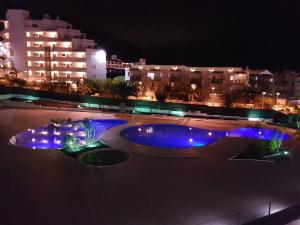 uma piscina com luzes azuis numa cidade à noite em Los Cristianos, Tenerife em El Guincho