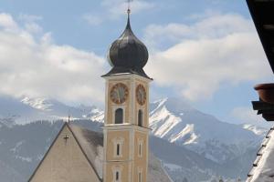 a church with a clock tower with mountains in the background at Bijou in den Bergen in Disentis