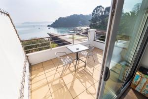 a balcony with a table and chairs looking out at the ocean at Hôtel BelleVue in Bréhat