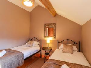 two beds in a small room with a mirror at Hayloft Cottage in Staintondale