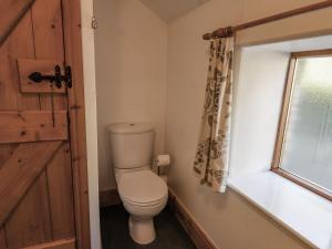 a bathroom with a toilet and a window at Hayloft Cottage in Staintondale