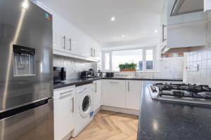 a kitchen with a stove and a washer and dryer at Prestbury Road in Cheltenham