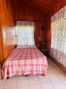 a bedroom with a bed with a red and white checked blanket at Lamanai Riverside Retreat in Orange Walk