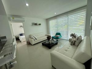 Una sala de estar con muebles blancos y una gran ventana. en Beachfront Bliss-2BR Haven Steps from Sandy Shores, en Cartagena de Indias
