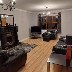 a living room with leather furniture and a fireplace at Large private detached home in Dungiven
