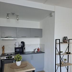 une cuisine avec des placards blancs et une table en bois dans l'établissement Studio de charme, à Saint-Maixent-lʼÉcole