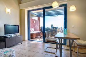 Best View Apartment 1. في برباتي: غرفة معيشة فيها تلفزيون وباب زجاجي منزلق