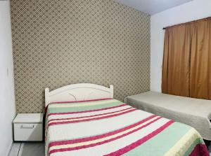 1 dormitorio con 1 cama con manta a rayas en Casa em Bombinhas Praia do Mariscal, en Bombinhas