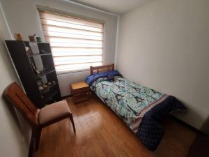 1 dormitorio con 1 cama, 1 silla y 1 ventana en Cómodo y acogedor apartamento, en Pasto