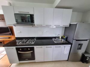 a kitchen with white cabinets and a stove and a microwave at Cómodo y acogedor apartamento in Pasto