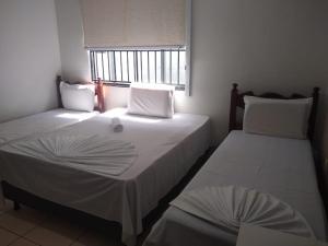 2 Einzelbetten in einem Zimmer mit Fenster in der Unterkunft Crystal Palace Hotel in Rolim de Moura