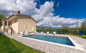 a swimming pool with chairs and a house at Apartman Butoniga Nature in Buzet