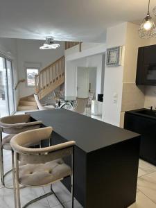 a kitchen with a black counter and some chairs at Appart duplex 87m2 près d’Airbus in Toulouse