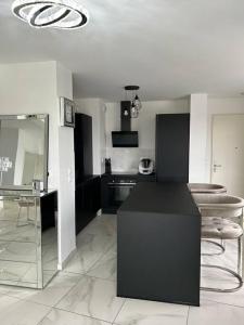 a kitchen with a black counter and some stools at Appart duplex 87m2 près d’Airbus in Toulouse