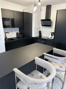 a kitchen with two white chairs and a counter at Appart duplex 87m2 près d’Airbus in Toulouse