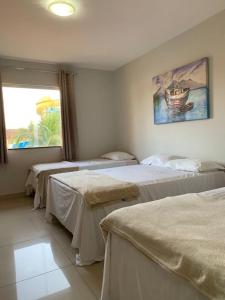 a room with three beds and a painting on the wall at JL Temporadas q 222 PortobelloPark in Porto Seguro