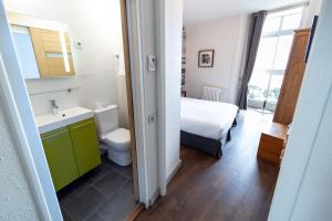 a bathroom with a bed and a sink and a toilet at Hôtel BelleVue in Bréhat