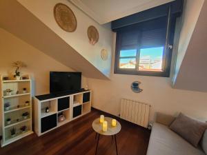 sala de estar con sofá, TV y mesa en El Cielo de Fomento, en Gijón