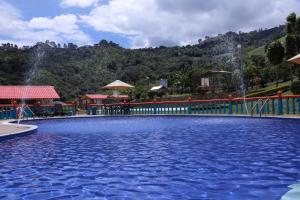 a large swimming pool with a waterfall in the background at Hotel Cafetero Valparaíso in La Vega