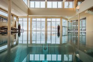 a swimming pool in a building with a large window at Gesundheits- & Wellness Resort Weissenbach 