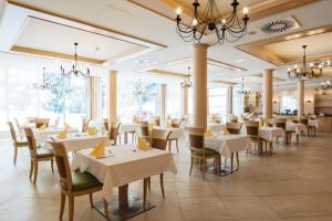 un restaurante con mesas y sillas blancas y ventanas en Gesundheits- & Wellness Resort Weissenbach, 