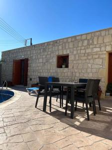 einen Tisch und Stühle auf einer Terrasse neben einer Steinmauer in der Unterkunft Fontana Traditional House in Anarita