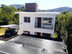 a white house with a car parked in front of it at Departamento Nuevo! 2 Dormitorios LA FALDA CORDOBA in La Falda