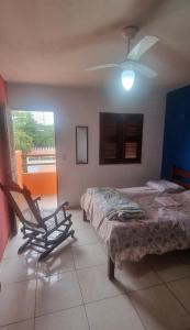 a bedroom with a bed and a chair and a ceiling fan at Suites Solar dos Arcanjos Guaramiranga in Guaramiranga