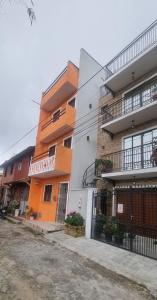 an orange and white building next to a street at Suites Solar dos Arcanjos Guaramiranga in Guaramiranga