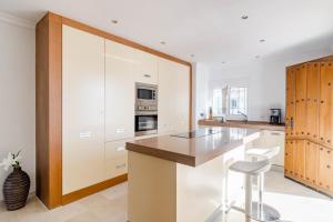 a kitchen with white cabinets and a counter with a stool at AGC28- Andalucia Garden Club by Roomservices in Marbella