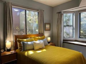 a bedroom with a yellow bed with two windows at Luxury Modern Townhome steps to ski lifts and downtown with Nature at your patio in Breckenridge