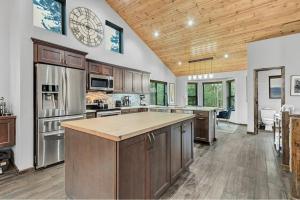 a large kitchen with wooden ceilings and a large island at Luxury Modern Townhome steps to ski lifts and downtown with Nature at your patio in Breckenridge