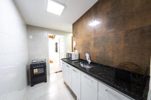 a kitchen with white cabinets and a black counter top at Jahu Center Casas Un 1 in Jaú