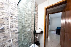 a bathroom with a glass shower with a sink at Jahu Center Casas Un 1 in Jaú