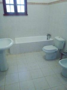 a bathroom with a toilet and a tub and a sink at Holiday Homes in Nazaré