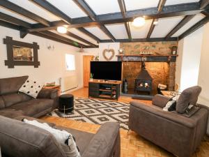 ein Wohnzimmer mit einem Sofa und einem Kamin in der Unterkunft Buarthau Cottage in Caernarfon