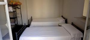 three beds in a small room with white sheets at Old Center Inn Alicante in Alicante